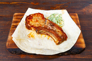 Delicious grilled ribs served with fresh cilantro and flatbread Savory vegetable pie served with fresh garnishes on a white plate