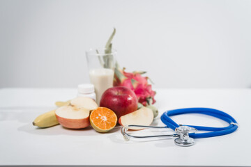 A table with mixed fruit and a stethoscope, symbolizing the connection between health, nutrition,medical care, promoting a balanced lifestyle wellbeing through healthy eating and wellness practices