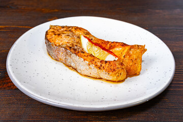 Grilled salmon with lemon served on a rustic wooden table Savory vegetable pie served with fresh garnishes on a white plate