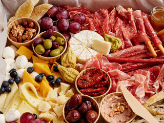A colorful charcuterie board features an array of cured meats, assorted cheeses, and fresh fruits, complemented by nuts and spreads, perfect for social gatherings