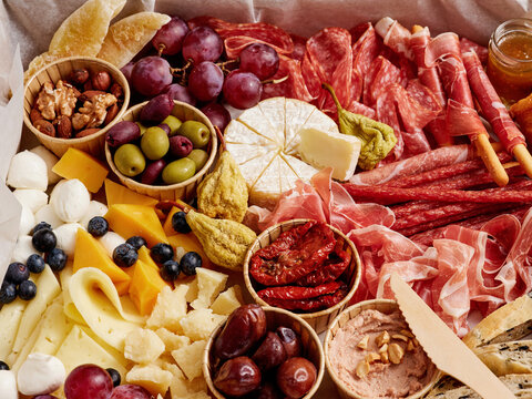 A colorful charcuterie board features an array of cured meats, assorted cheeses, and fresh fruits, complemented by nuts and spreads, perfect for social gatherings