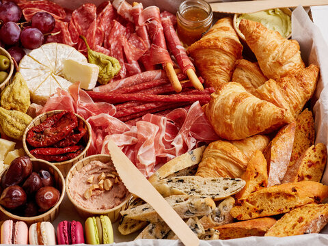 A beautifully arranged selection of meats, cheeses, baked goods, and fruits invites guests to indulge at a festive gathering. Colors and textures delight the senses