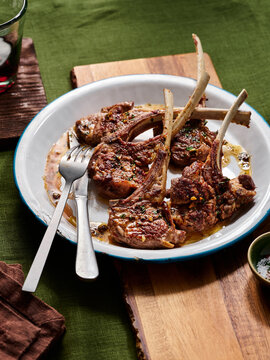Tender lamb chops are beautifully grilled, garnished with fresh herbs and arranged on a rustic wooden board, inviting a delicious meal experience
