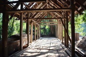Fototapeta premium Rustic wooden bridge under construction, showing framework and sunlight.