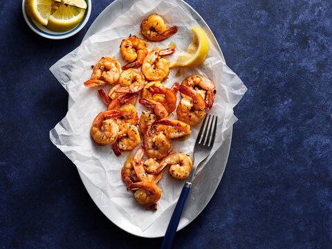 A platter showcases juicy shrimp garnished with lemon wedges, perfect for a casual dining experience. This dish is ideal for seafood lovers and sharing