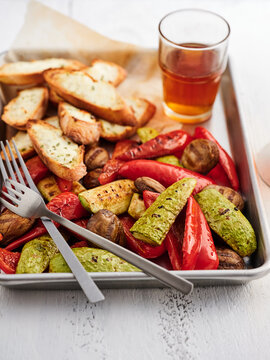 A colorful platter features grilled zucchini, peppers, and mushrooms, accompanied by crispy garlic bread and a chilled beverage, creating a delightful summer meal