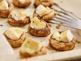 Savory mushroom caps are baked until tender and topped with creamy cheese. The dish is served warm on a rustic tray, ideal for a casual gathering or party