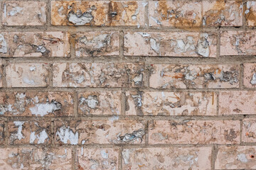 Old dirty pink brick wall. There are many remains of removed paper advertisements. Close-up. Background. Texture.