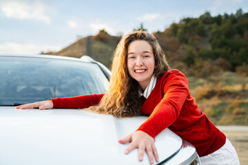 Satisfied happy young woman in casual wear hugging her new car. Cheerful caucasian girl feeling...