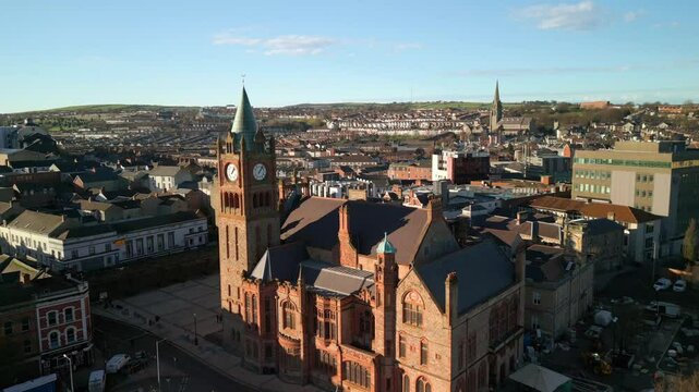 Aerial shot of the Guildhall in Derry-Londonderry, NI on a bright sunny day. The camera pulls back to reveal the River Foyle and the Peace Bridge. Filmed in 4K at 60fps and in Rec709 color space.