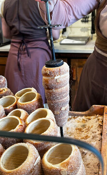 Pastry chef baking trdeln&iacute;k or kurtos kalacs, traditional hungarian sweet pastry, sprinkling sugar