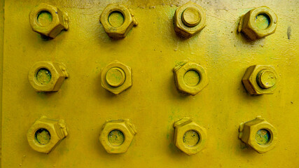 The bolts and nuts used for wall decoration are neatly arranged and symmetrically spaced painted in yellow