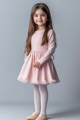 Fototapeta premium Cute girl in a pink dress, isolated on gray.