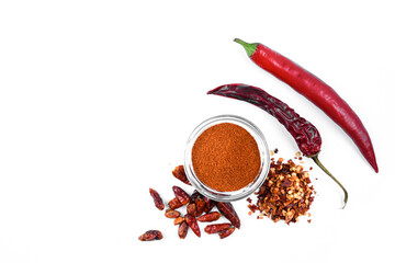 Minimalistic still life with red pepper in various stages.  whole chili peppers, dried peppers, crushed chili flakes and ground red pepper in a glass