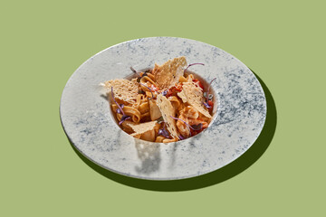 A vibrant and colorful plate of pasta topped with cherry tomatoes, fresh herbs, and crispy parmesan