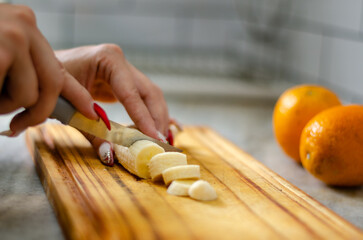 Close up woman hands cutting fruit on a wood table with oranges behind