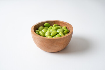 Edamame beans in wooden bowl on white background