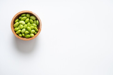 Edamame beans in wooden bowl on white background