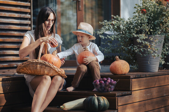 Mother and son with pumpkins enjoying autumn sunny day outdoors