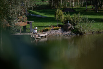 Boy fishing on a tranquil pond dock.