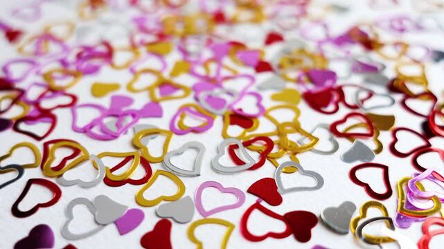 Valentines background. Hearts confetti on white background for Valentines Day. Love concept. Glitter confetty heatrs golden, red and pink . 4k slow motion footage