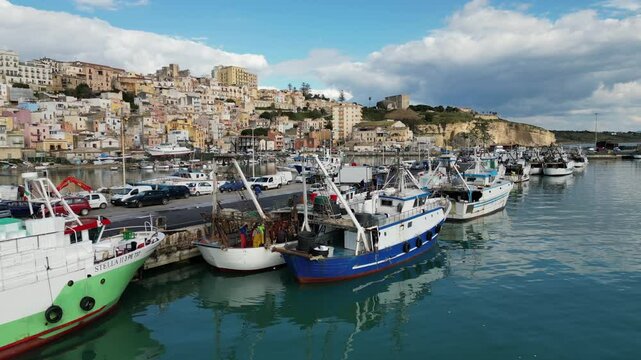 Aerial view of fishing boats unloading freshly caught fish in small port of Sciacca, industry and commerce in Sicily Italy
