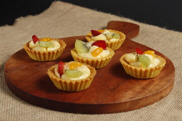 delicious fruit pie on a wooden baking sheet on a black background