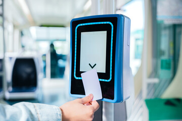 Close-up of a hand inserting a ticket into an electronic validation machine inside public...