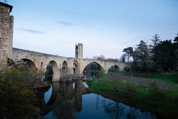Fototapeta premium Medieval stone bridge leading to picturesque village in catalonia