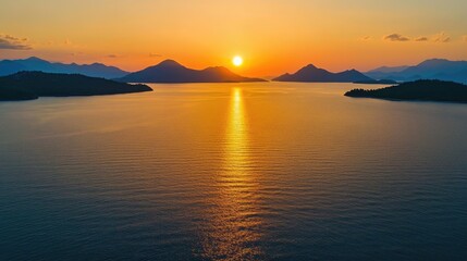 Fototapeta premium Tranquil aerial view of a sunset over the sea, featuring an orange sky, the sun setting into the ocean, and calm water reflecting the warm light.