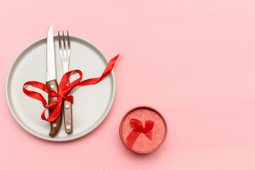 Valentine's Day, Womens day table serving with cutlery, plate and red napkin, gift box on pink background. Romantic dinner, love, date concept. Top view flatlay