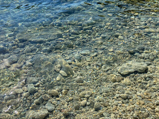 Crystal clear water with pebbles and stones on the beach 