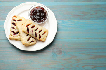 Delicious puff pastries and jam on light blue wooden table, top view. Space for text