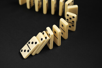 Domino effect. Tiles falling on black background