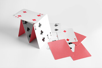 Collapsed house of playing cards on light background