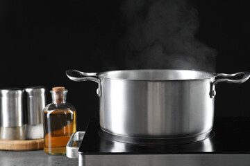 Metal pot on stove against black background