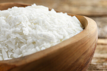 White soy wax flakes in bowl on table, closeup
