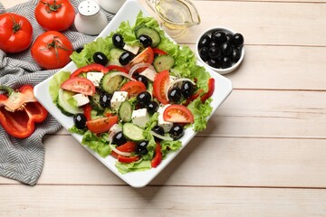 Delicious fresh Greek salad on white wooden table, flat lay