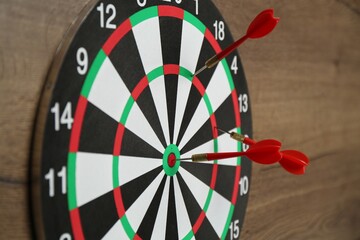 Dart board and red arrows on wooden background, closeup