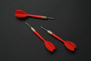 Red dart arrows on black background, flat lay