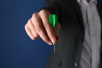 Fototapeta premium Man holding dart on blue background, closeup