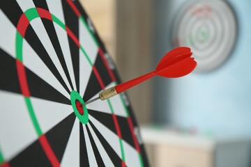 Red arrow hitting target on dart board indoors, closeup