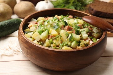 Delicious okroshka soup with kvass and ingredients on white wooden table, closeup