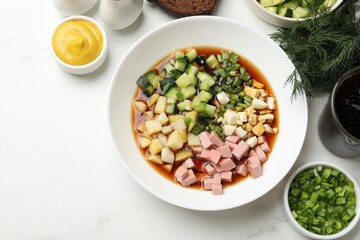Tasty okroshka soup with kvass and ingredients on white marble table, flat lay. Space for text