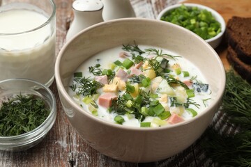 Delicious okroshka soup in bowl on wooden table, closeup