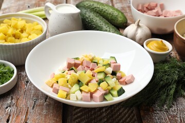 Ingredients for okroshka soup in bowl on wooden table, closeup