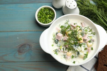 Delicious okroshka soup served on light blue wooden table, flat lay. Space for text