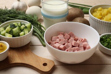 Fresh ingredients for okroshka soup on light wooden table, closeup