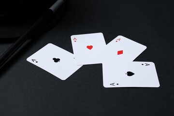Playing cards, hat and magic wand on black background, closeup