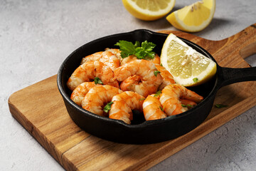 Cooked red shrimps prawn with spices in a pan, served with fresh herbs and lemon